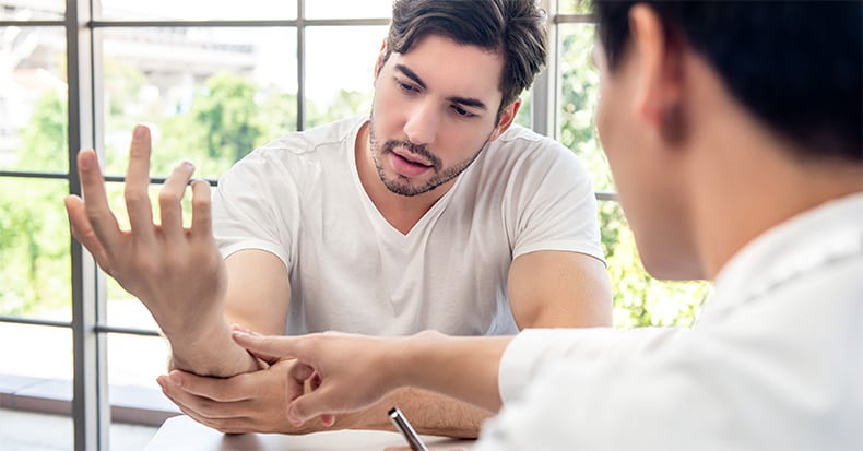 male patient consulting with doctor about wrist muscle pain from exercise