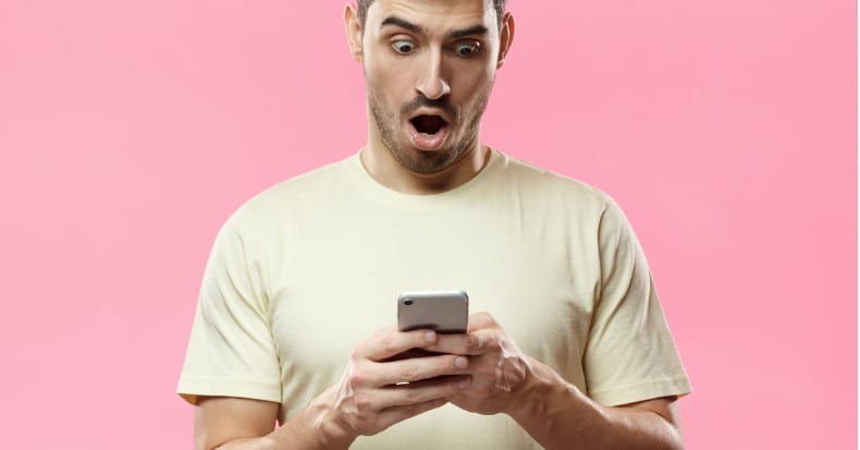 Portrait of young man isolated on pink background looking agitated at picture