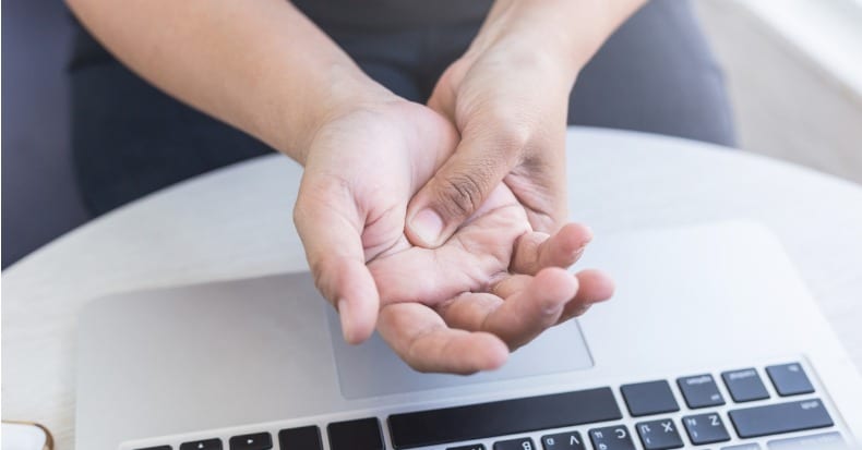 Woman holding and pressing or touching her hand while working with