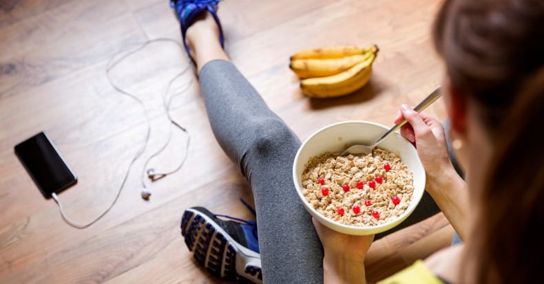 Young girl eating a oatmeal with berries after a workout fitness