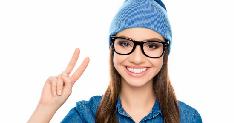 Portrait of smiling hipster woman in glasses showing two fingers