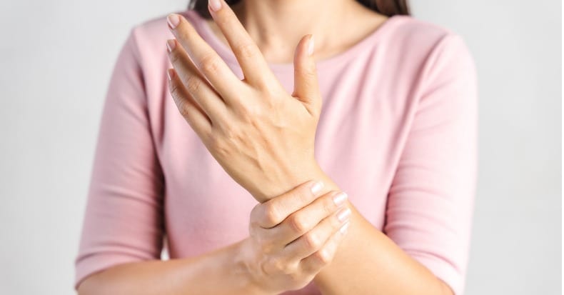 Closeup young woman holds her wrist on white background hand injury