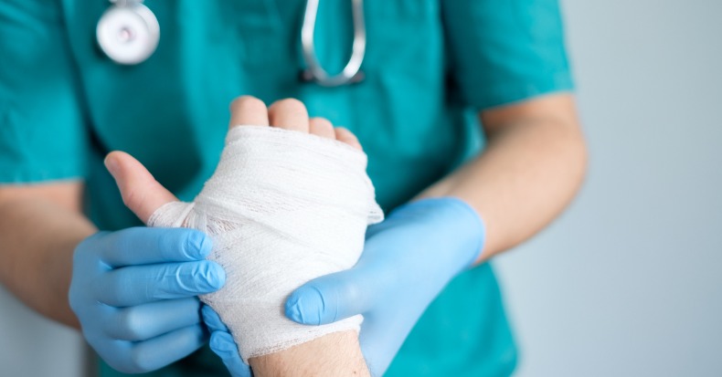 Close up of doctor bandaging one hand after an accident