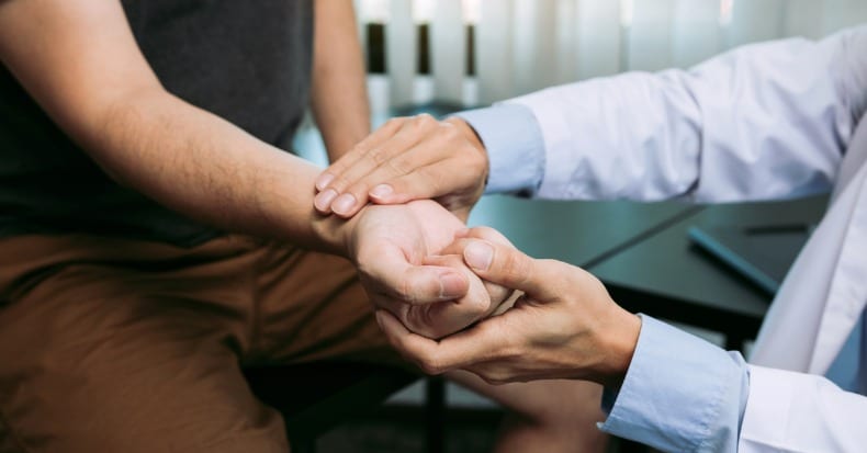 Physical therapist checks the patient wrist by pressing the wrist