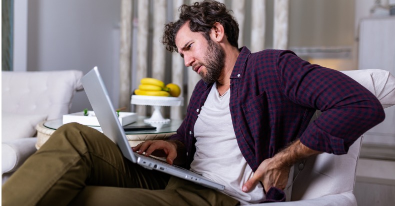 Tired man freelance worker stretch in sofa suffer from sitting long