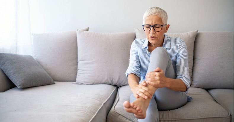 Middleaged woman suffering from pain in leg at home closeup