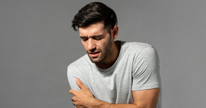 Young caucasian man suffering from shoulder pain studio shot in gray