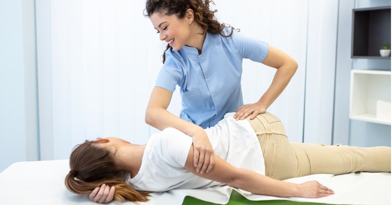 Young woman doctor chiropractor or osteopath fixing lying womans back